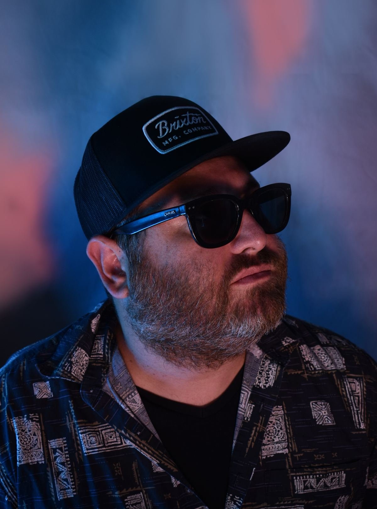 Hans Nüsslock of The Cabbys in a Brixton cap and sunglasses under blue light
